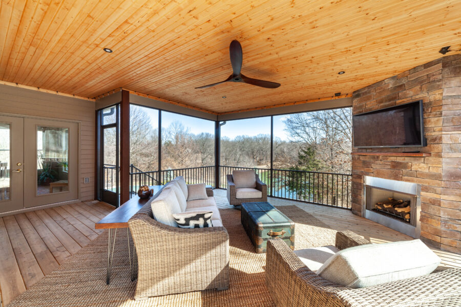 Furnished screened porch with a stacked-stone fireplace, a mounted television, and a wood-plank ceiling