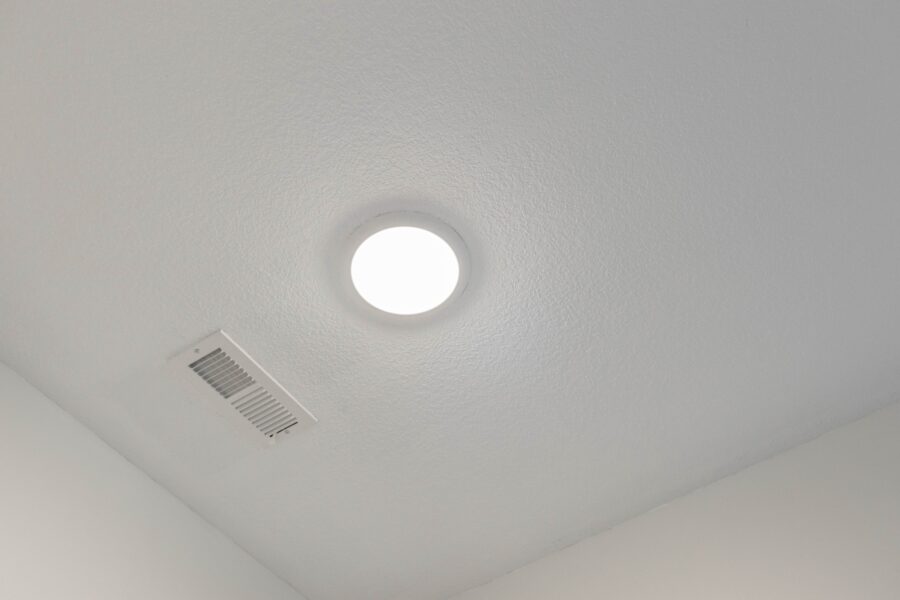 Painted white ceiling with a round light fixture and a ventilation grille